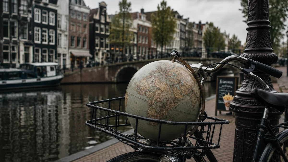 Globus in einem Fahrradkorb an einem niederländischen Kanal als Symbol für internationale Einflüsse auf typisch holländisches Essen