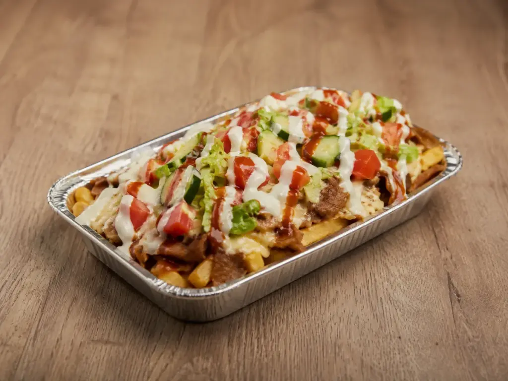 Kapsalon mit Pommes, Fleisch, geschmolzenem Käse, Salat und Soßen in einer Aluschale